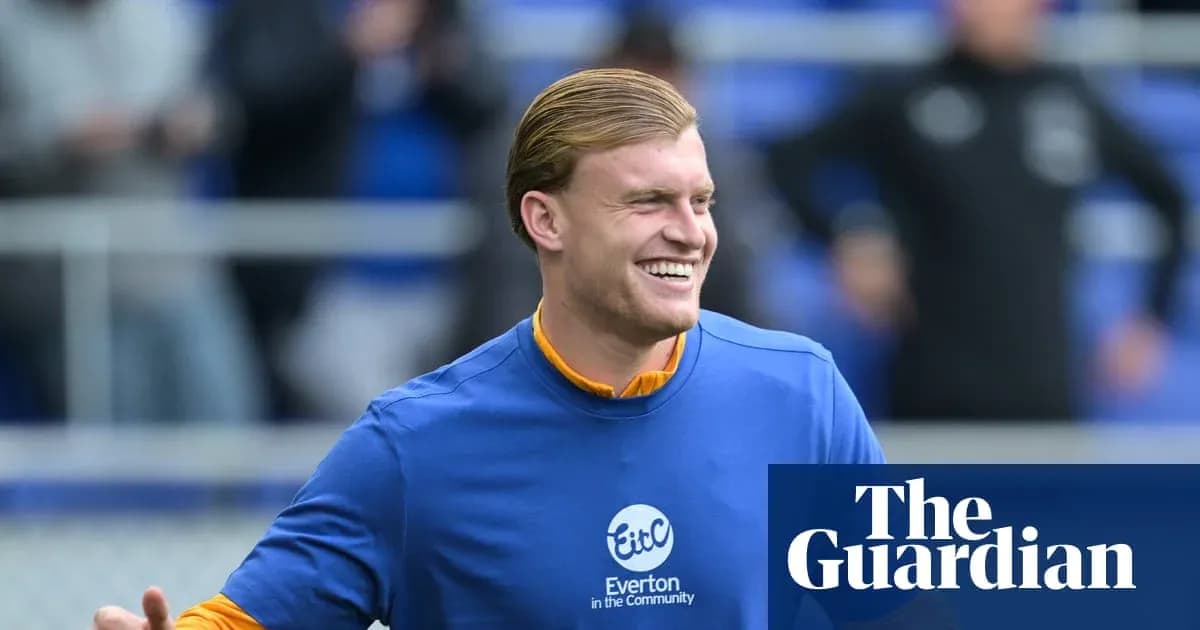 Игрок в синей футболке улыбается на поле