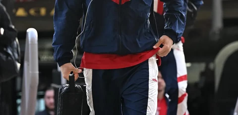 Игрок в спортивном костюме идет к автобусу