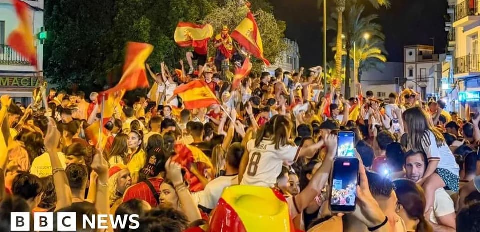 Толпа празднует с флагами Испании ночью