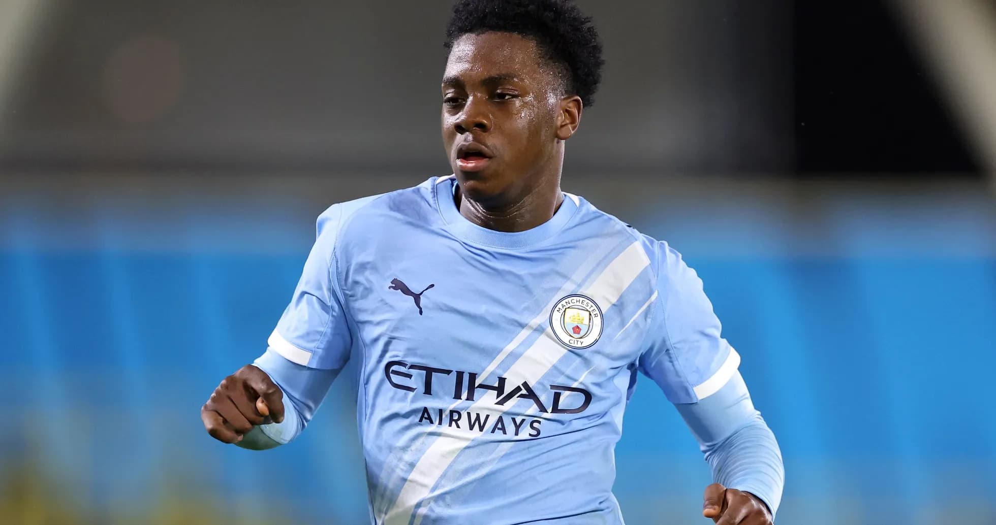 Игрок Manchester City бежит по полю в синей форме