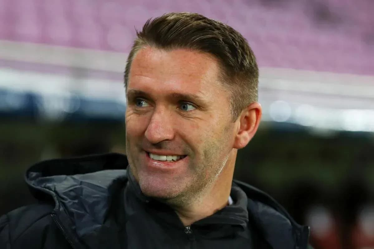 Тренер улыбается на стадионе перед матчем