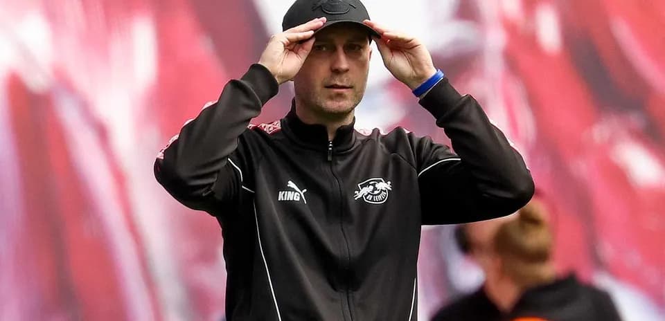 Тренер команды adjusts his cap on the sideline