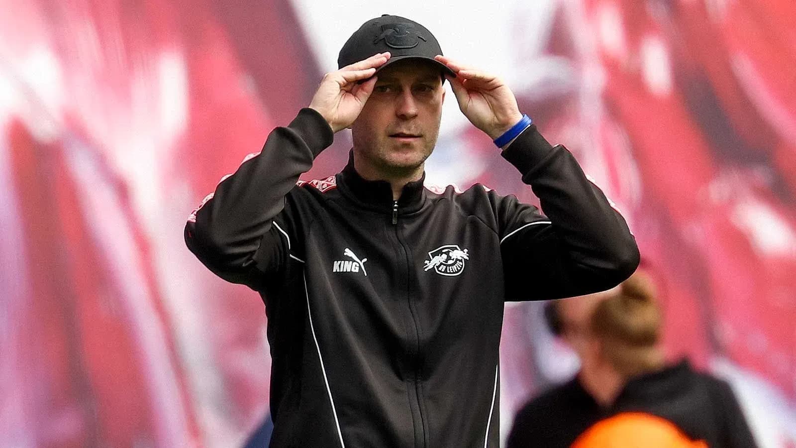 Тренер команды adjusts his cap on the sideline