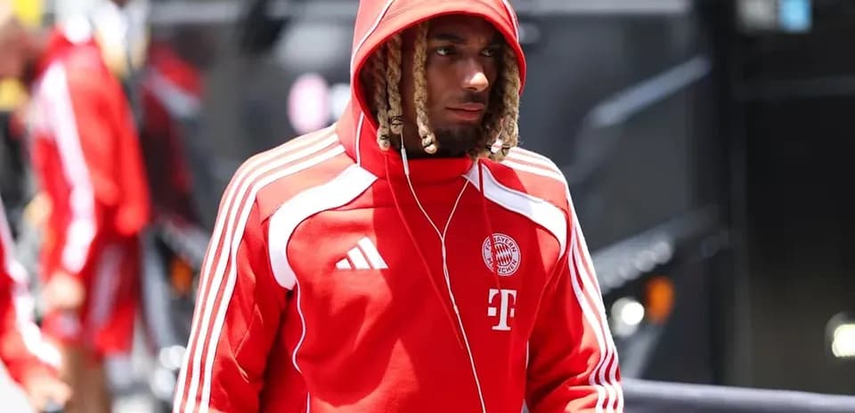 Игрок в красном костюме Bayern Munich идет к автобусу