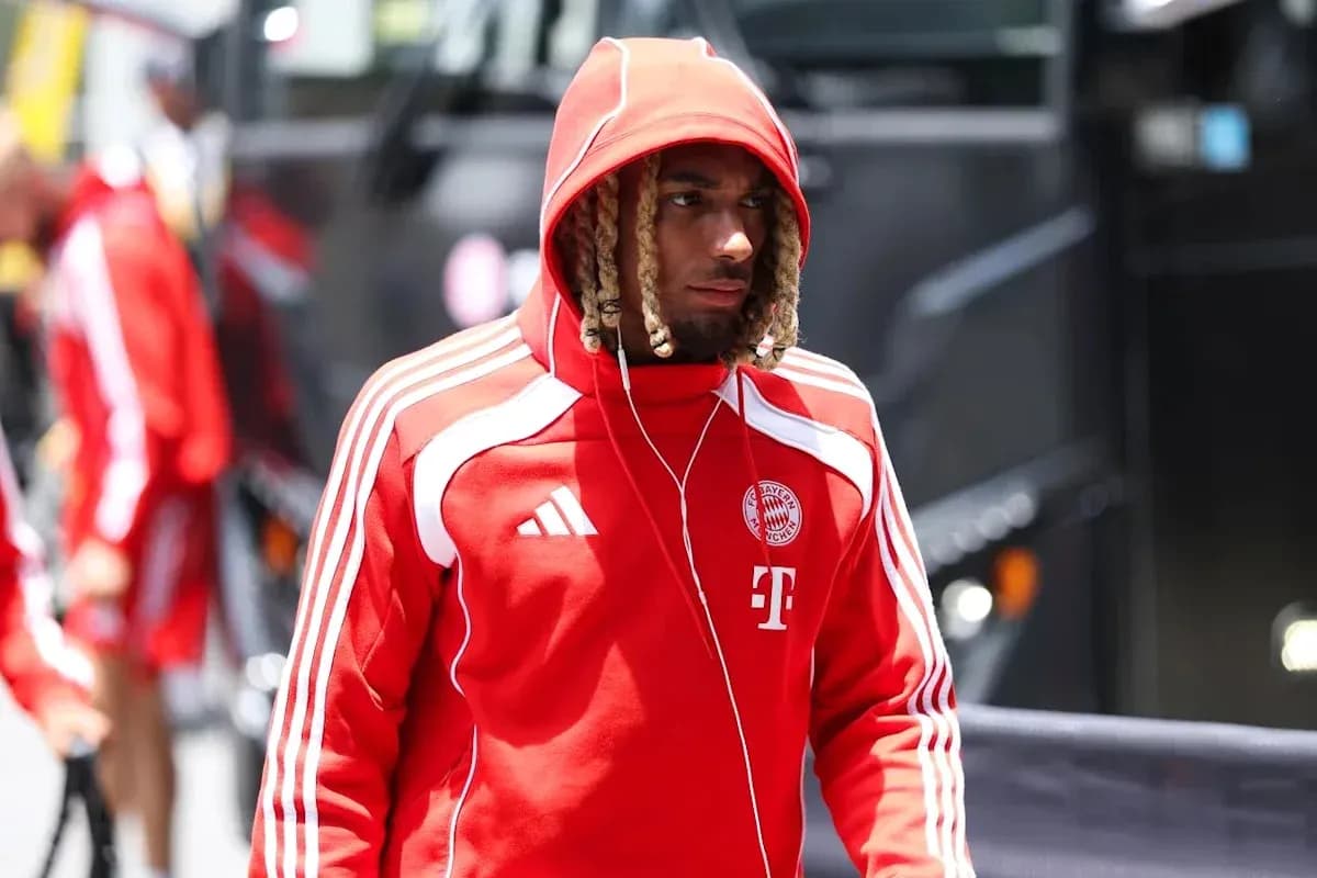 Игрок в красном костюме Bayern Munich идет к автобусу