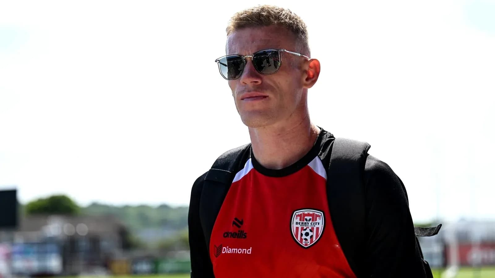Игрок в футболке Derry City на улице в солнечный день