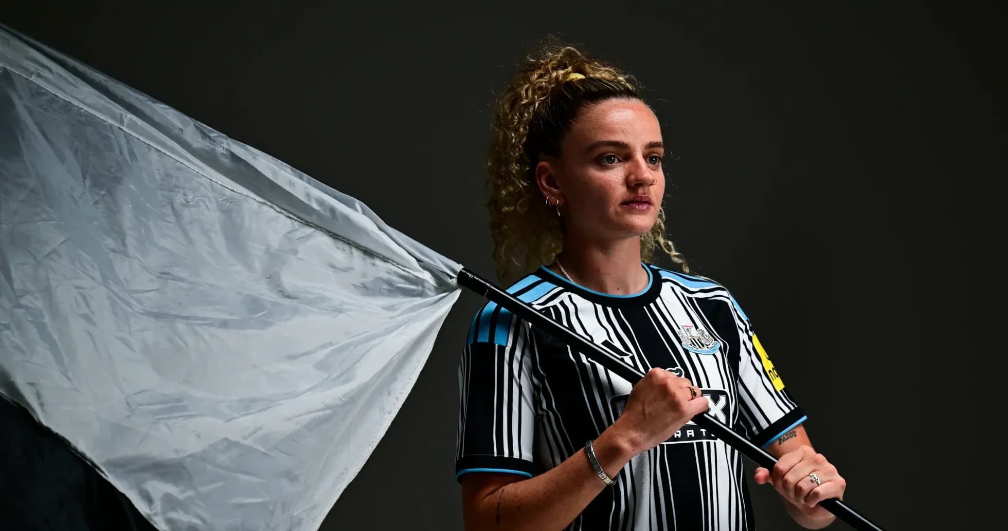 Игрок в форме Newcastle с флагом на фоне