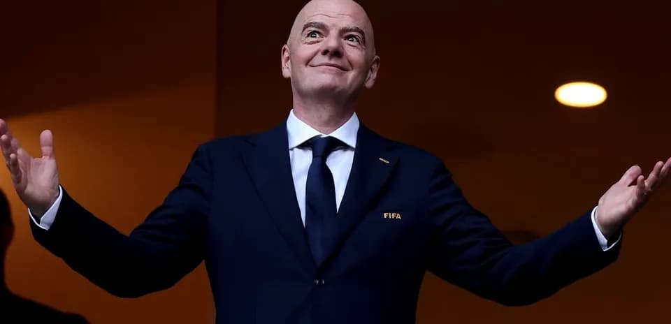 Председатель FIFA с поднятыми руками на трибуне