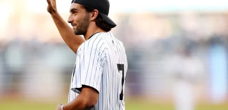 Человек в бейсбольной форме приветствует зрителей