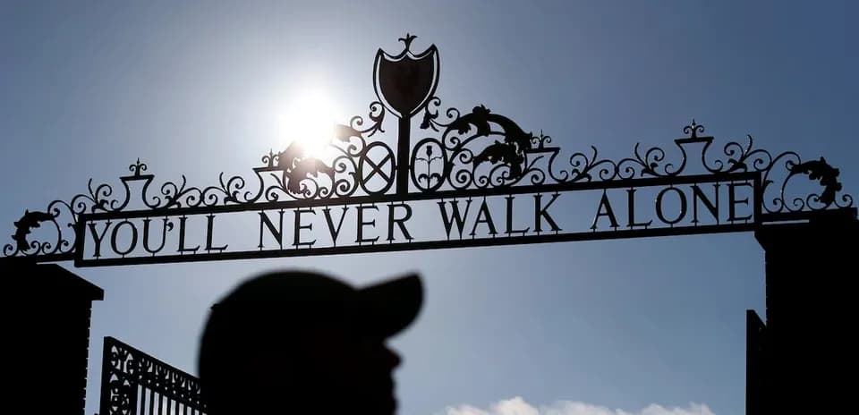 Знак 'YOU'LL NEVER WALK ALONE' на фоне солнца