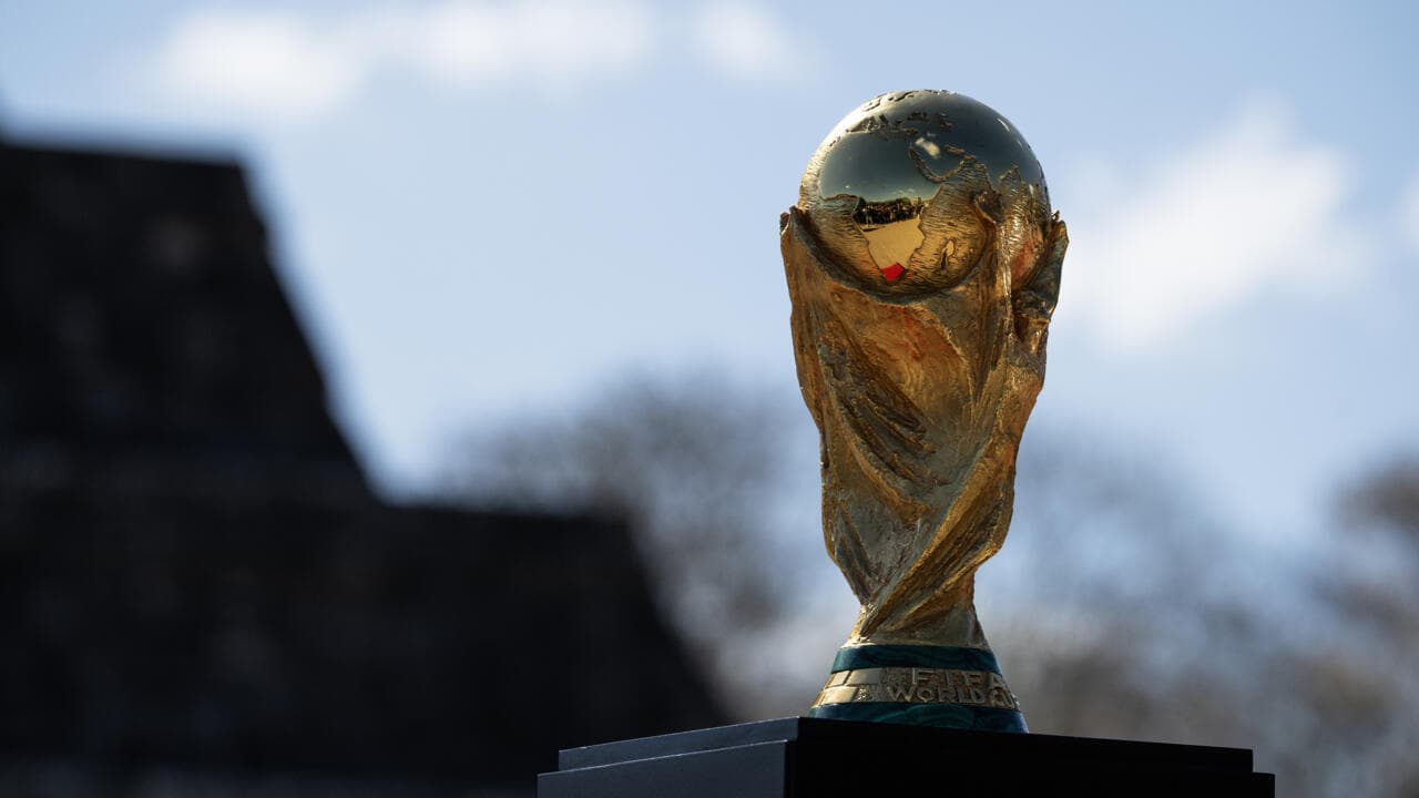 Золотой кубок FIFA на фоне неба