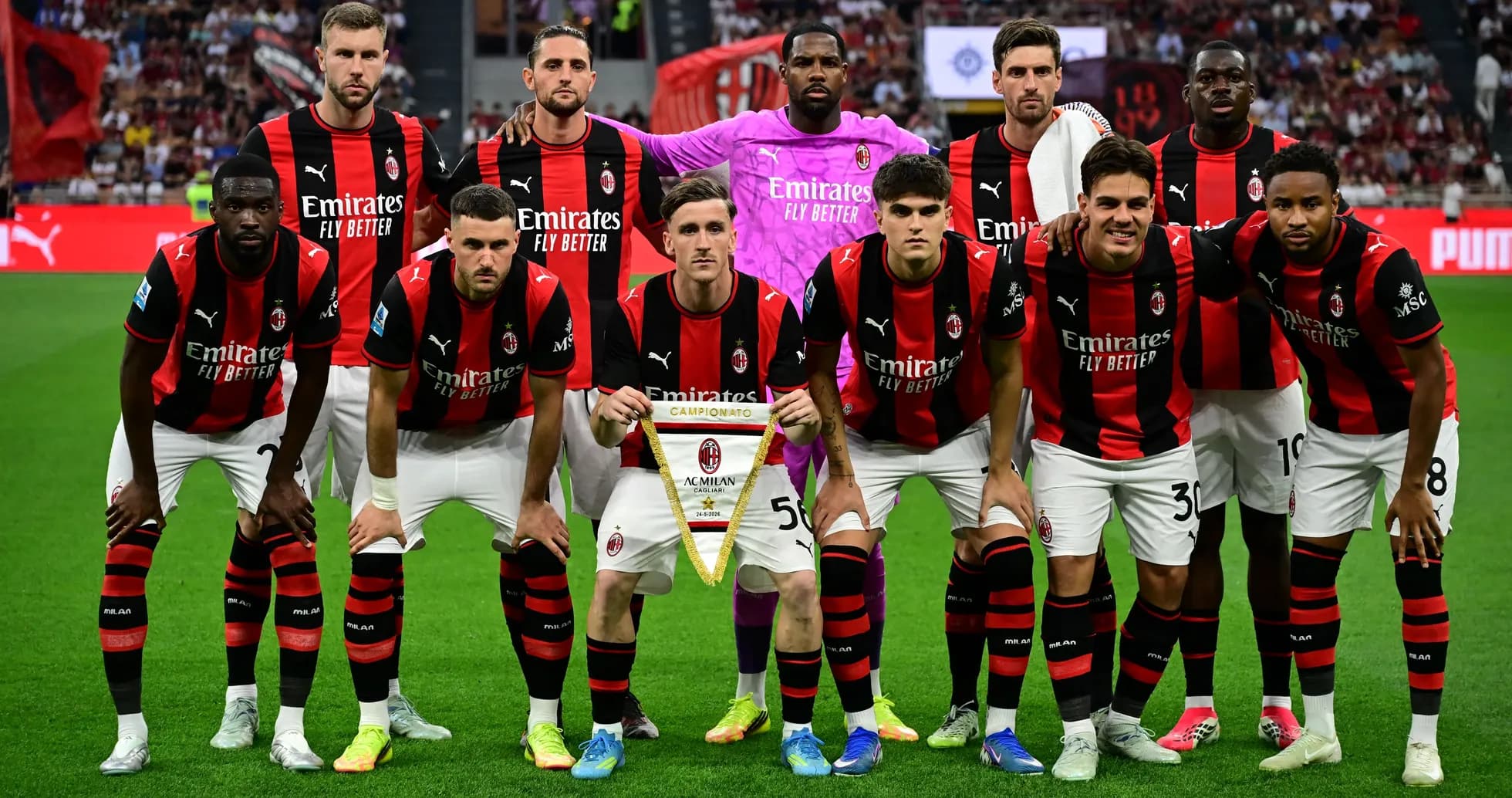 Команда AC Milan позирует с трофеем на поле